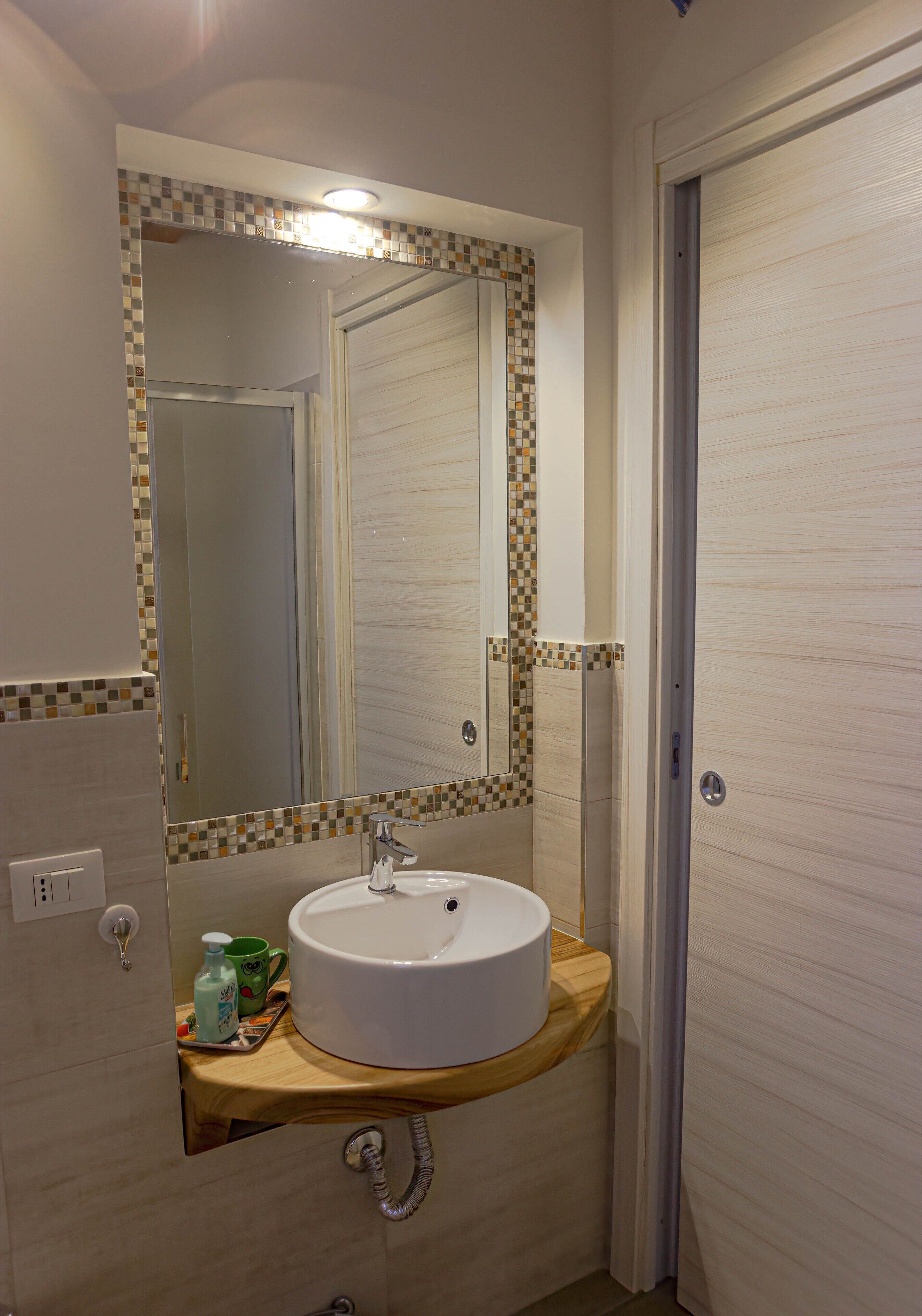 Un baño con un lavamanos blanco, un espejo y un salpicadero de azulejos.