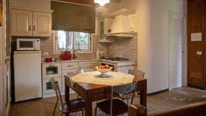 A kitchen with wooden cabinets, a microwave, a gas stove, and a dining table with chairs.