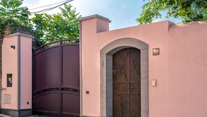 A pink building with a large wooden door and a metal gate.