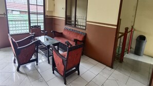 A dining area with a table and four chairs, a window with a view of buildings, and a trash bin. - Hotel O Penginapan Al-asharNearWarung Acil Ubai (Boemirata)