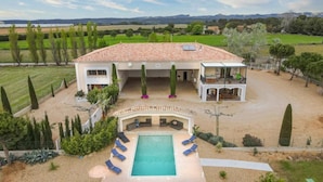 Una casa grande con techo de tejas, piscina y patio cubierto.