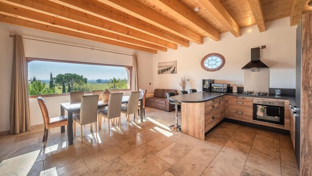Una cocina moderna con comedor, vigas de madera en el techo y vistas al exterior.