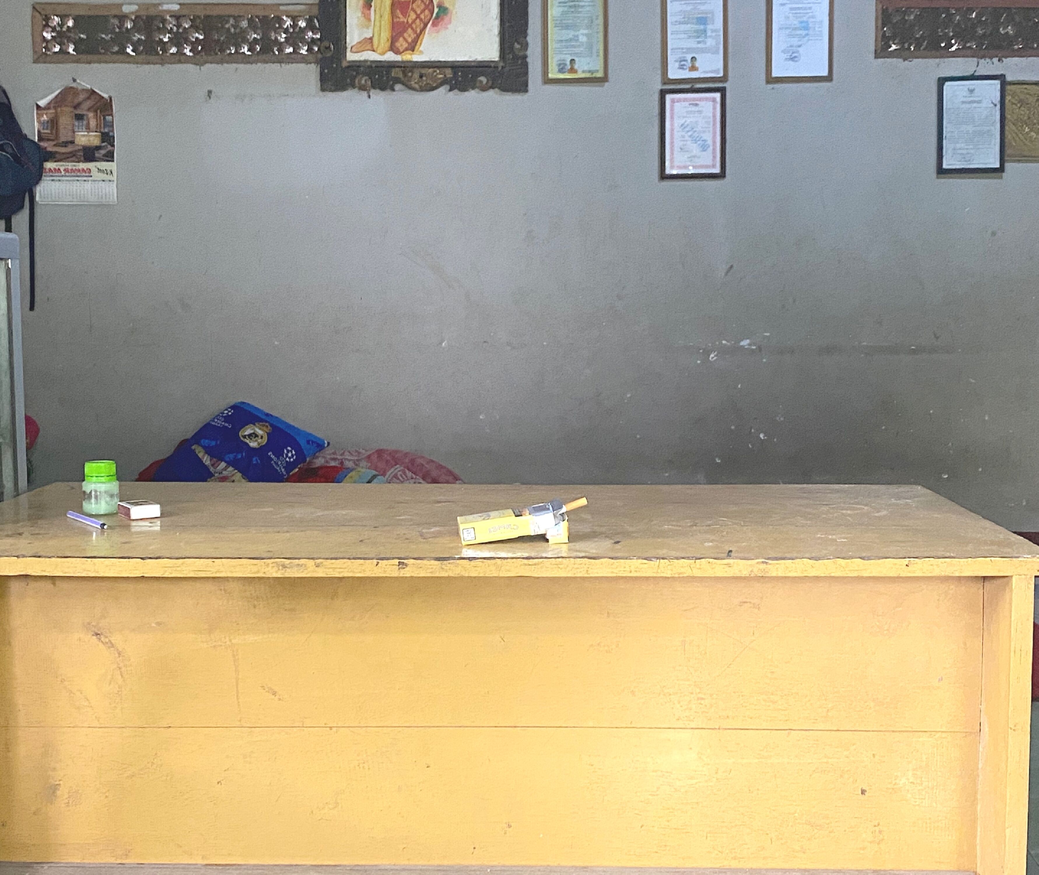 Una mesa de recepción con superficie de madera, una botella verde y un objeto blanco encima.