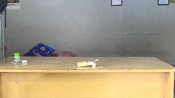 Una mesa de recepción con superficie de madera, una botella verde y un objeto blanco encima.