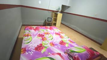 A small bedroom with a bed, a TV, and a wooden cabinet.