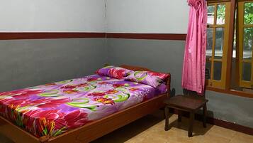 Un letto singolo con una coperta a fiori in una stanza con pavimento piastrellato e una finestra con tende.