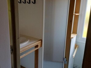 A bathroom with a wooden vanity, a white sink, and a vertical striped shower curtain. - Chalets with pets, between Sioul Valley and Combraille (Échassières)