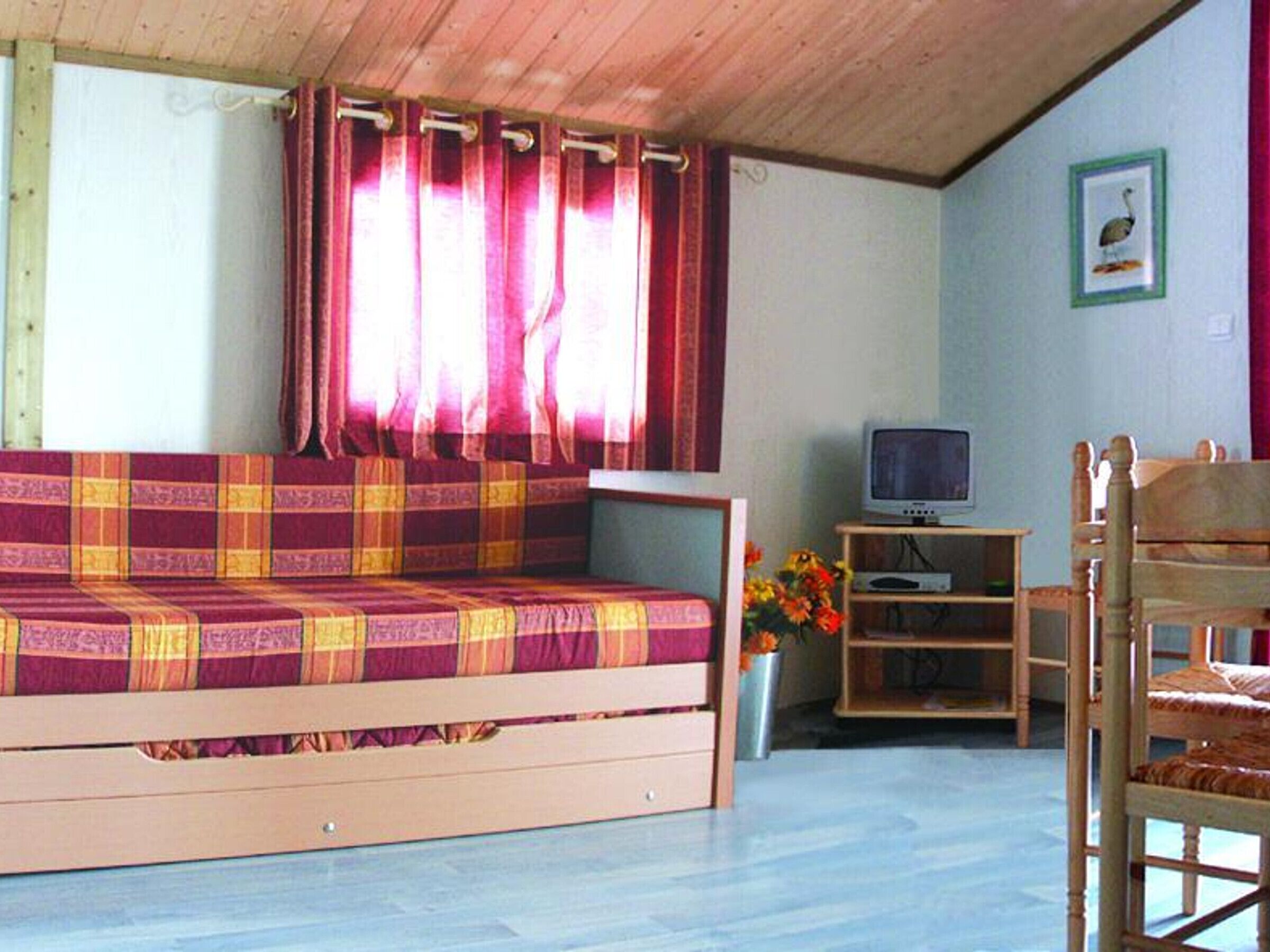Une pièce confortable avec un canapé, un téléviseur et une chaise en bois.