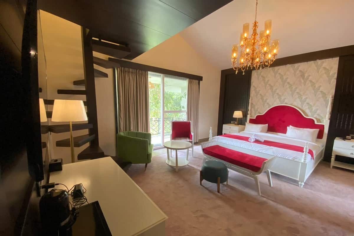 A hotel room with a bed, a desk, a chair, a round table, and a chandelier.
