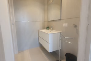 A modern bathroom with a white vanity, a mirror, and a towel rack. - BnButler - 48 Monza Ave. (Milano)