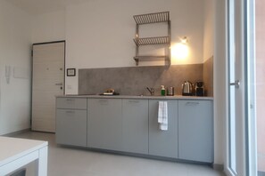 A modern kitchen with grey cabinets, a countertop, a built-in shelf, and a kettle. - BnButler - 48 Monza Ave. (Milano)