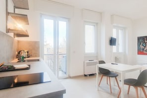 A modern kitchen with a dining area, large windows, and a flat-screen TV. - BnButler - 48 Monza Ave. (Milano)