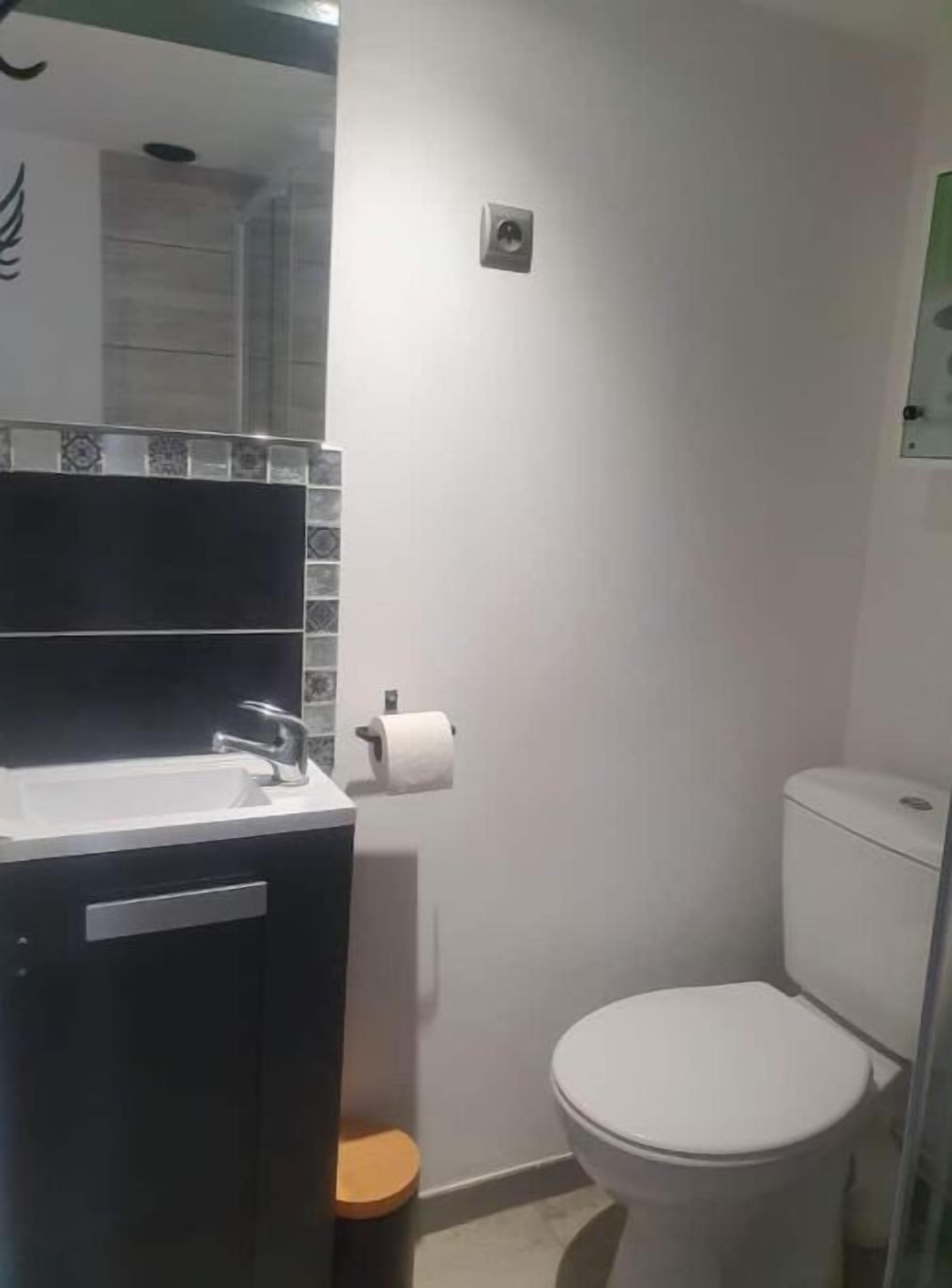 Un baño con lavamanos blanco, un inodoro y un cubo de basura pequeño.