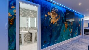 A modern bathroom with a marble wall, a sink, and a mirror.