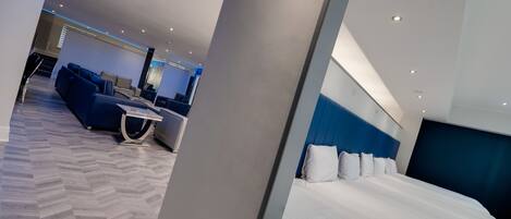 A modern hotel room with a large bed, a sofa, and a desk.