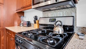 A kitchen with a black stove, a kettle, a toaster, and a blender on the counter. - Rancho Sol A | 1BR Legacy Villa (La Quinta)
