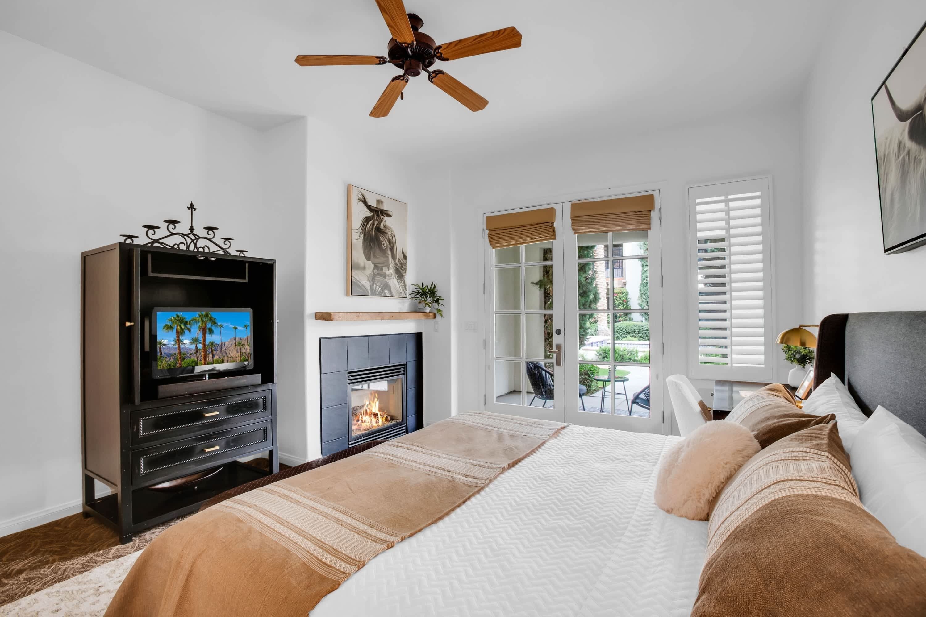 A bedroom with a TV, fireplace, and a view of the outdoors.
