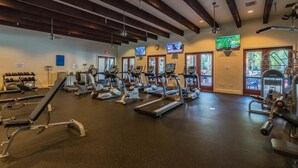 Un gimnasio con cintas de correr, bicicletas estáticas y máquinas de pesas.