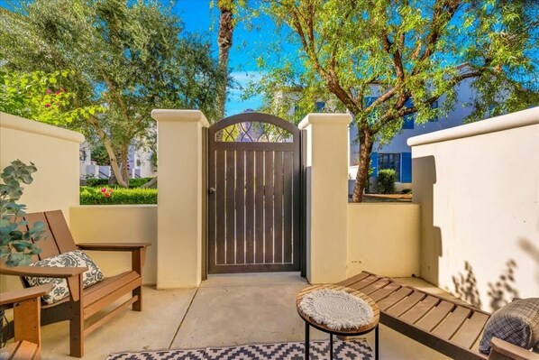 A courtyard with a wooden bench, a small table, and a gate.