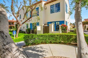 A two-story building with a white facade and blue shutters, surrounded by well-maintained greenery and trees. - Rancho Sol C | Studio Legacy Villa (La Quinta)