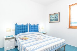 A bedroom with a bed, two bedside tables, a nightstand, a window, and a painting on the wall. - Piazzetta Trilo Porto 30m From The Beach (Loiri Porto San Paolo)