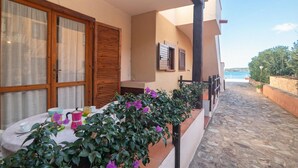 Ein Balkon mit Esstisch, Topfpflanzen und Blick aufs Meer.