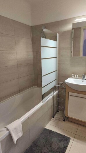 Un bagno con vasca, lavandino e doccia.