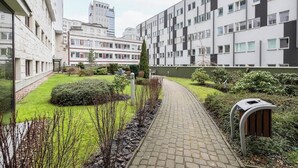 Une cour intérieure dotée d’un chemin pavé, entourée de verdure et bordée d’une rangée de bâtiments au style architectural moderne.