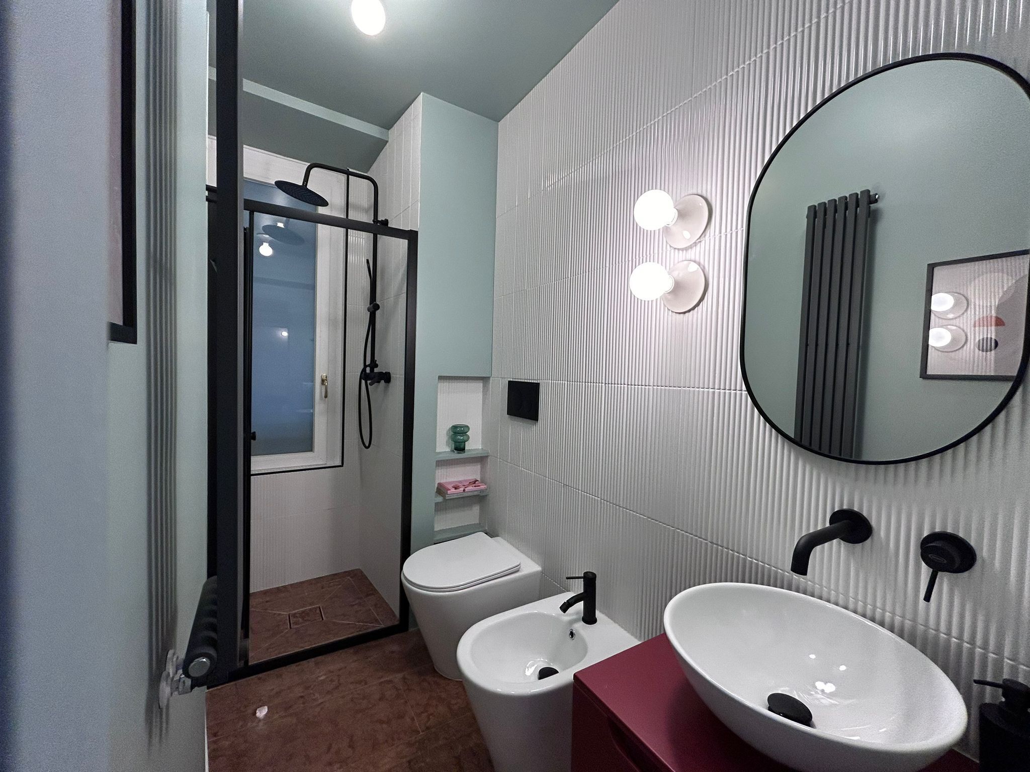A modern bathroom with a glass shower enclosure, a white toilet, a bidet, and a vanity with a large mirror.