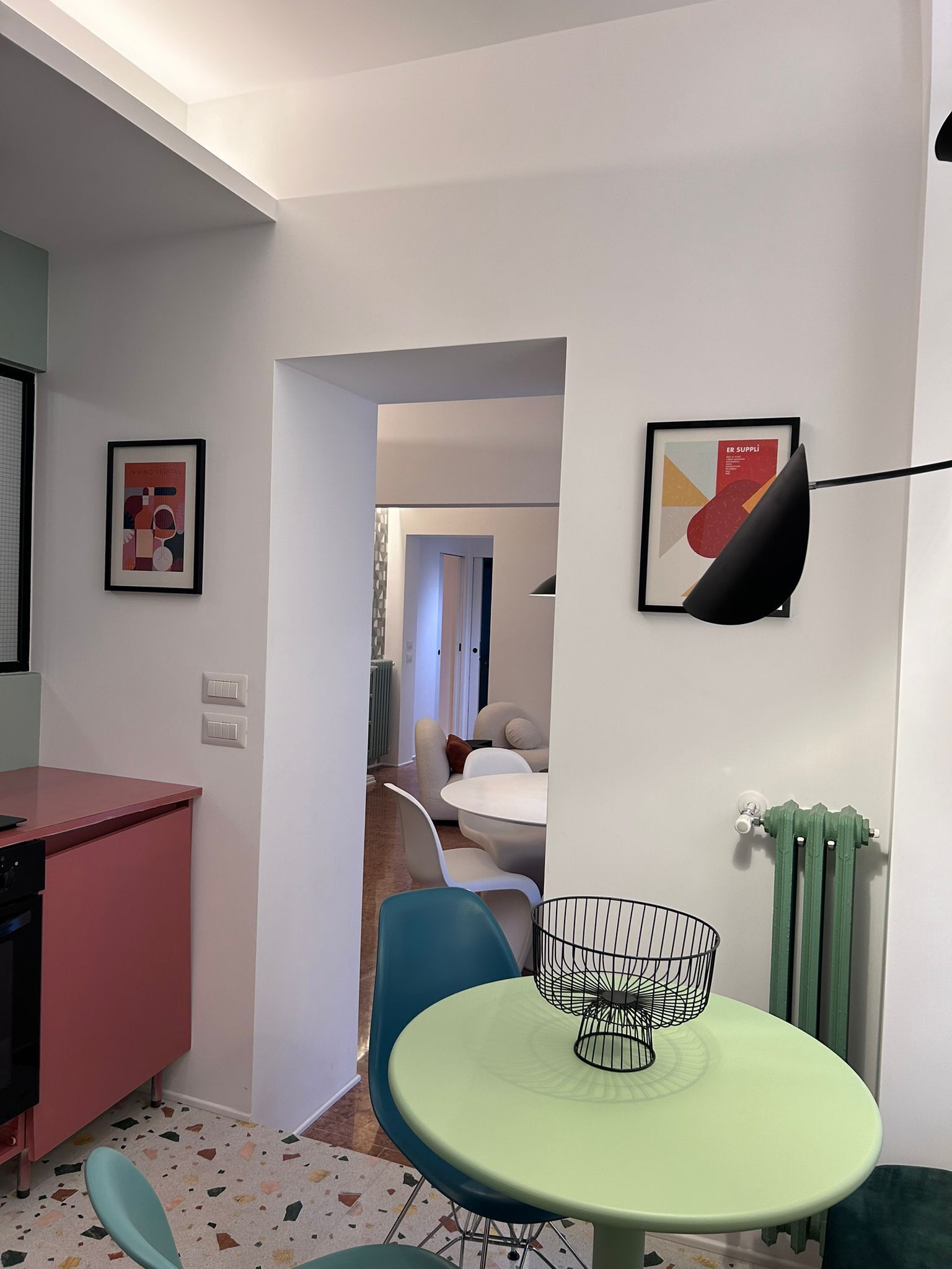 A modern kitchen with a dining area, a kitchen island, and a dining table with chairs. There is a framed picture on the wall and a radiator on the wall.