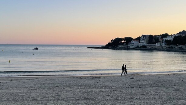 A beach with a clear sky, calm sea, and a few boats. There are buildings in the background. - Studio 70, Centre, Proche des Plages (Saint-Palais-sur-Mer)