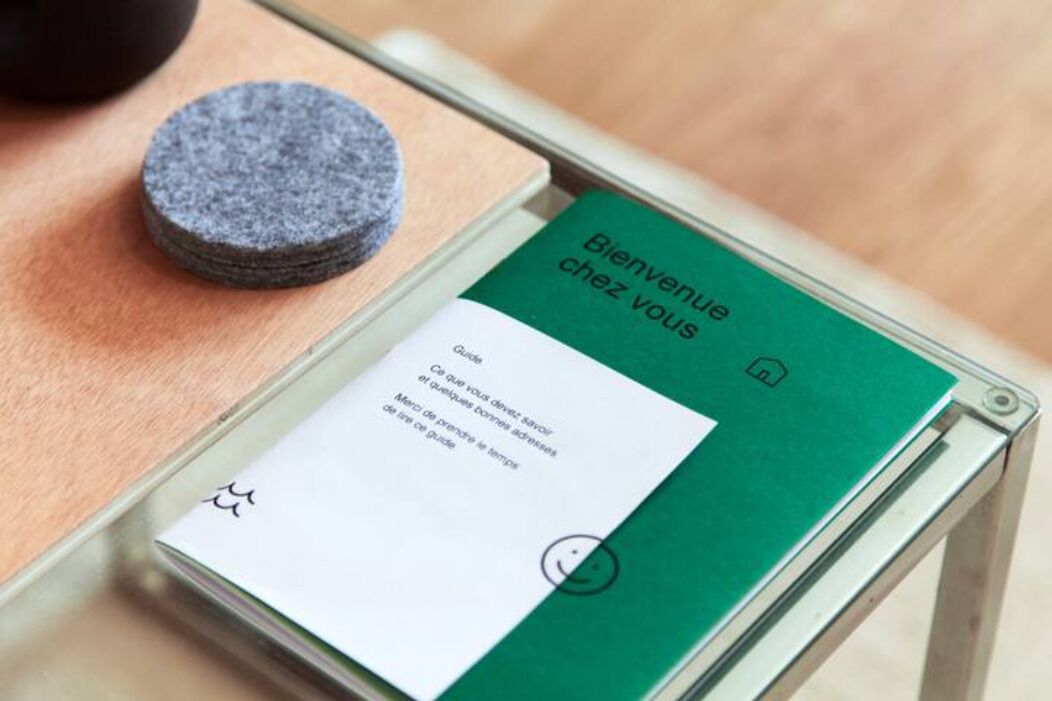 A welcome card with a green cover and a white card underneath, placed on a glass table.