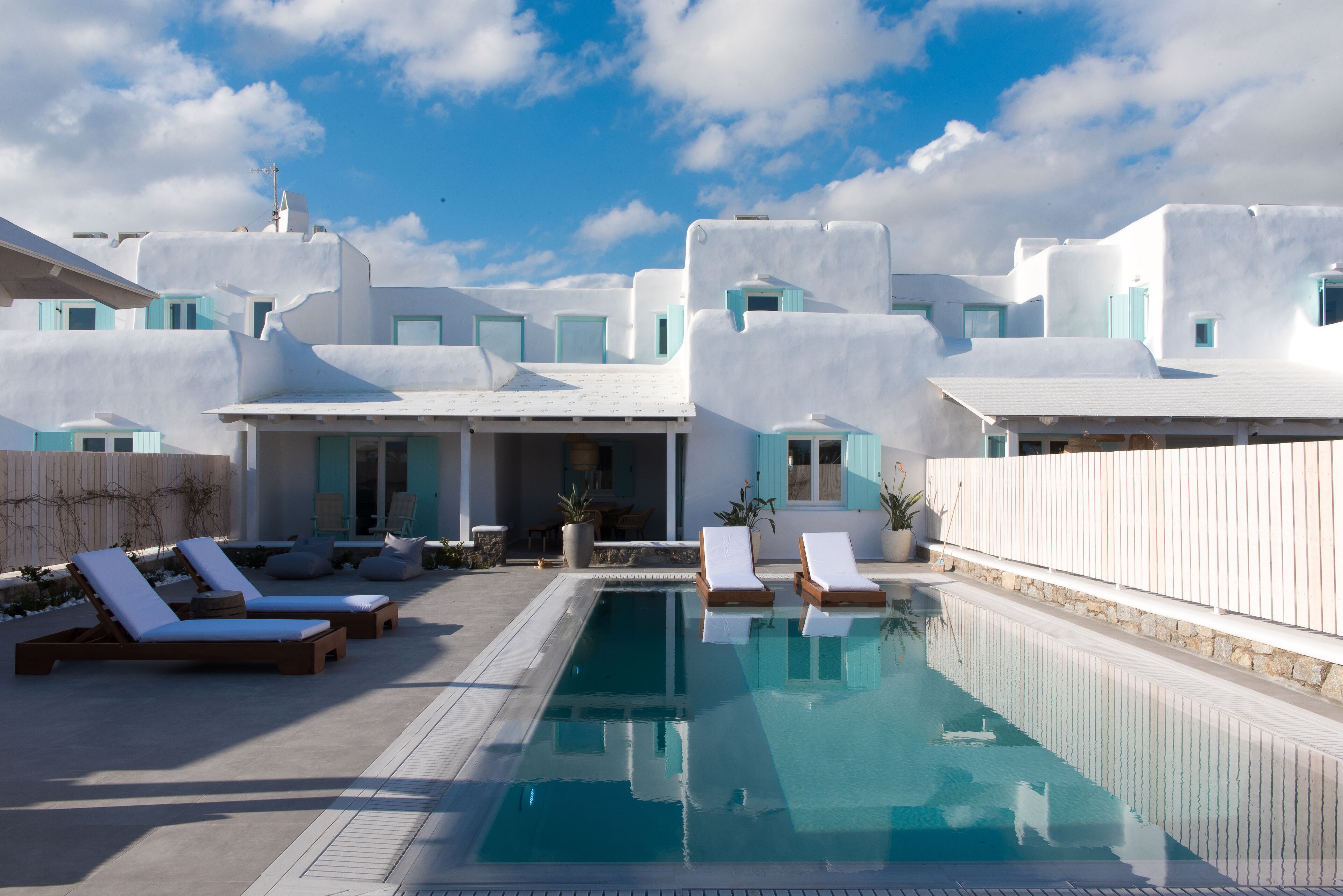 A pool area with lounge chairs and a clear sky.