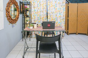 A small dining area with a table, chairs, a laptop, and a decorative mirror.