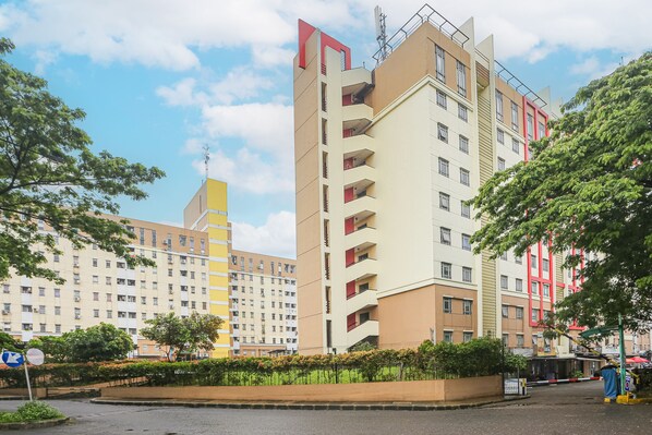 A multi-story residential building with balconies, a gated entrance, and a clear sky.