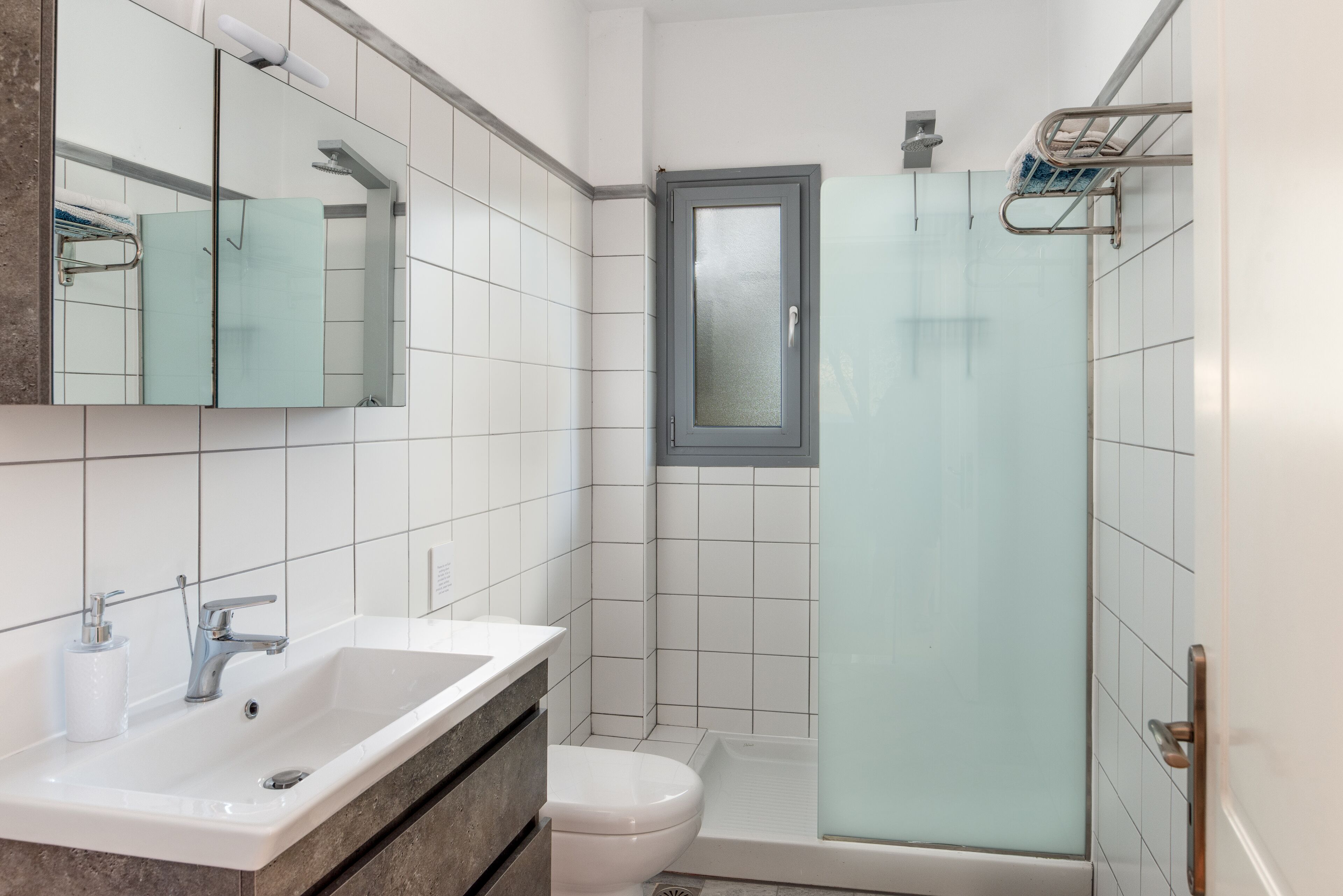 A modern bathroom with a white sink, a glass shower enclosure, and a toilet.