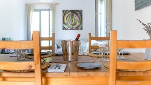 A dining area with a wooden table set for four, including plates, cutlery, and glasses. - Costa Avithos Mansion (Kefalonia)