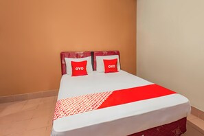 Een bed met een wit en rood beddekleed, twee kussens met de tekst 'OYO' en een rood-wit gestreepte deken.