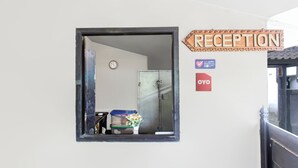 A reception area with a sign, a clock, and a metal door.