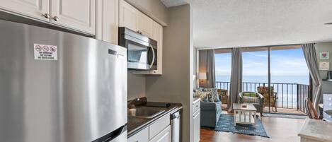 A modern kitchen with stainless steel appliances, a dining area with a view, and a balcony with a view.