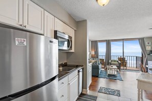 A modern kitchen with stainless steel appliances, a dining area with a view, and a balcony with a view. - Oceanfront at Carolina Reef w/ Pools, 2 Bds (North Myrtle Beach)