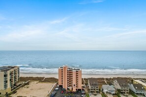 Ein Strandhotel mit zentralem Gebäude, Parkplatz und Meerblick.