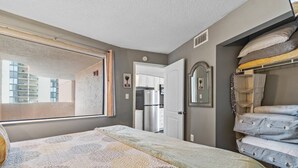 Une chambre à coucher avec un lit, une armoire, un miroir et une vue sur l’extérieur.