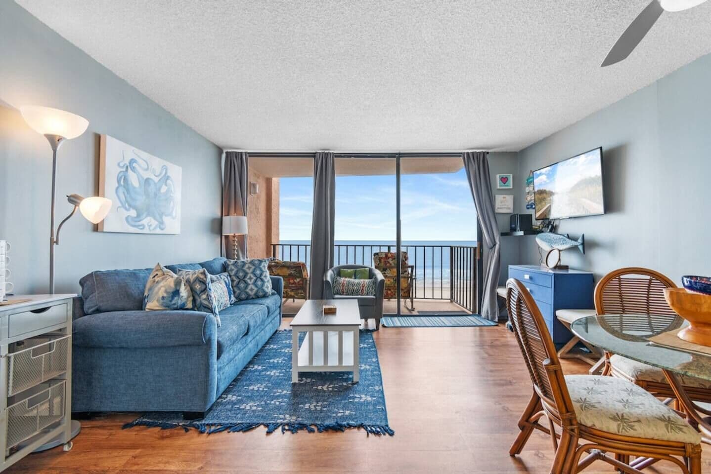A living room with a sofa, coffee table, and a dining area with chairs and a table.