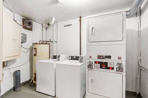 A compact laundry room with two washing machines and a dryer, a water heater, and a utility cabinet. - Oceanfront at Carolina Reef w/ Pools, 2 Bds (North Myrtle Beach)
