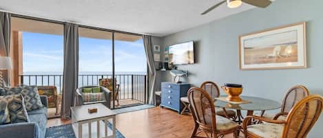 A spacious balcony with a view of the sea, furnished with a sofa, chairs, and a dining table.