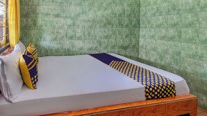 Una stanza con un letto, una finestra con tende gialle e pareti rivestite di piastrelle verdi.