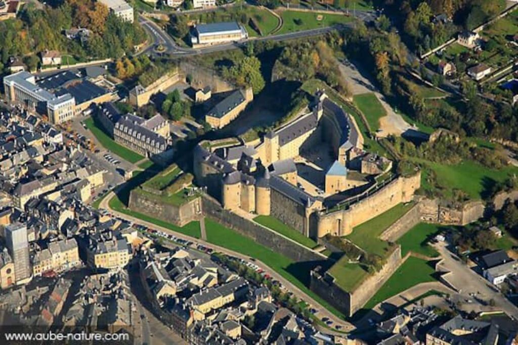 An aerial view of a historic castle surrounded by residential buildings and a road.