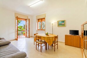 A dining area with a table and chairs, a sofa, a TV on a cabinet, and a painting on the wall. - Casa Gallipolina with sea view (Gallipoli)