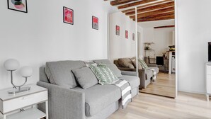 Un salon moderne avec un canapé gris, une table d’appoint blanche et un plafond en bois.